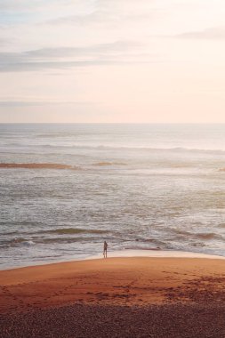Portekiz 'in Vila Nova de Milfontes kasabasında Atlantik Okyanusu üzerinde insan ve günbatımı