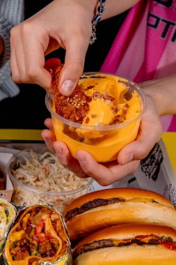 Kızarmış tavuk kanadını peynir sosuna batıran kız.