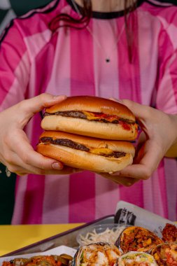 Elinde iştah açıcı bir burger tutan bir kız.