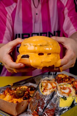 Elinde peynirli hamburger tutan bir kız.