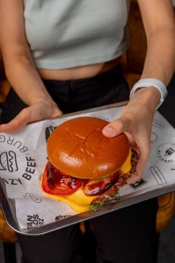 Elinde iştah açıcı bir burger tutan bir kız.