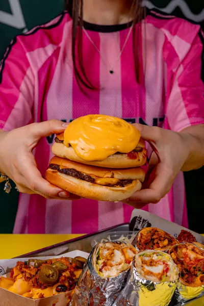 Elinde peynirli hamburger tutan bir kız.