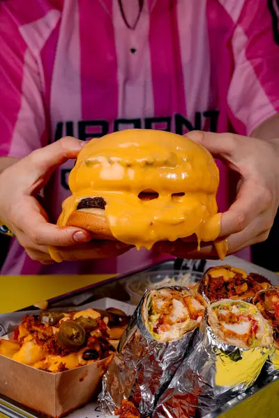 Elinde peynirli hamburger tutan bir kız.