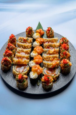 Siyah tabakta somonlu Japon suşisi ruloları.