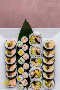 Suşi beyaz kare tabakta maki sarıyor.