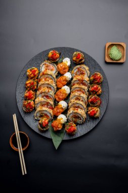 Siyah arka planda siyah bir tabakta Tempura suşi rulosu