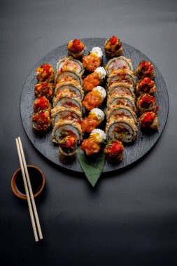 Siyah arka planda siyah bir tabakta Tempura suşi rulosu