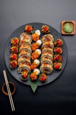 Siyah arka planda siyah bir tabakta Tempura suşi rulosu