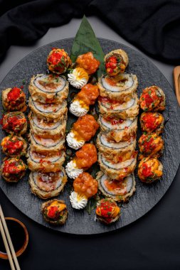 Siyah arka planda siyah bir tabakta Tempura suşi rulosu