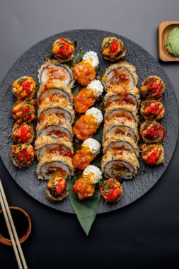Siyah arka planda siyah bir tabakta Tempura suşi rulosu