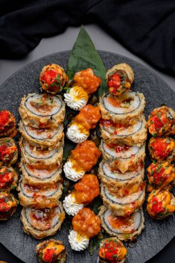 Siyah arka planda siyah bir tabakta Tempura suşi rulosu