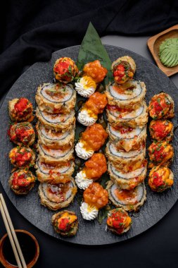 Siyah arka planda siyah bir tabakta Tempura suşi rulosu