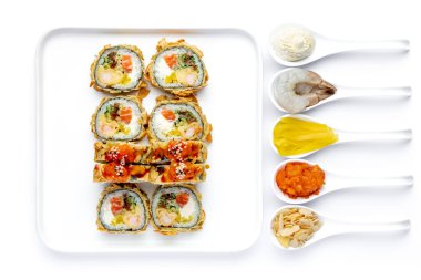 Sushi roll on a white plate on a perfectly white background with ingredients for it in white spoons isolated