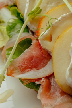 Prosciutto, armut, peynir ve soslu sandviç.