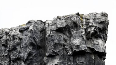 Beyaz zemin üzerinde pürüzlü pürüzlü kayalık bir uçurum.