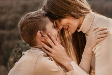 Sevgi dolu bir anne ve okul çağında bir oğul doğayla burun buruna. Mutlu kadın ve oğlanın yüz yüze, ovuşturan burunların yakın portresi. Anne ve oğul arasındaki hassas an, mutlu annelik ve çocukluk kavramı..