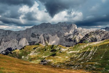 Karadağ 'ın Durmitor Ulusal Parkı' ndaki Dinaric Alpleri üzerindeki dramatik fırtına bulutlarıyla dolu dağ manzarası. Yazın yeşil dağ vadisinde yağmur ve güneş kontrastlı Alp manzarası.
