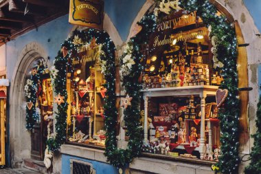 Colmar, Fransa - 4 Ocak 2020. Noel süsleri, çelenkler, oyuncaklar ve şekerlemelerle dolu hediyelik eşya dükkânı. Alsace kasabasında kostüm ve ışıklarla cam ekran.