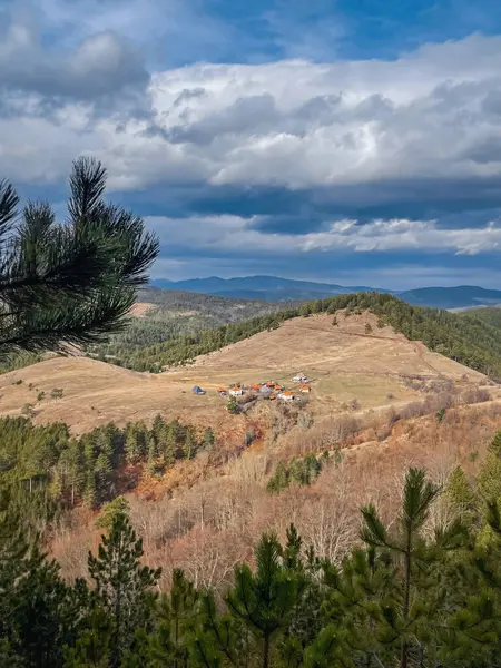 Mountain landscape in Zlatibor, Serbia. Small rural houses in a valley surrounded by mountains and forest. Pastoral Balkan landscape, picturesque view in serbian country side, view from mountain top.