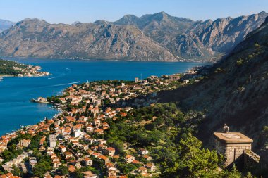 Ortaçağ kale duvarlarında tek başına oturan ve Boka Kotorska 'ya bakan tanınmayan biri. San Giovanni şatosundan Kotor Körfezi 'nin manzarasının keyfini çıkaran adam Eski Şehir ve marinaya bakıyor..