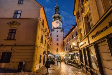 Bratislava, Slovakya - 11 Temmuz 2018. Ortaçağ tahkimatlarından Michaels Gate en eski kasaba binasıdır. Saat kulesi, kafeli tarihi caddeler, kaldırımlar akşamları aydınlatılıyor..