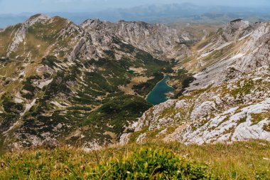 Bobotov Kuk dağının zirvesinden manzara. Durmitor Ulusal Parkı 'ndaki Skrcka gölleri ve uzak yeşil vadisiyle Alp yaz manzarası. Karadağ 'da Dinarica yoluyla maceralı yürüyüş gezisi.