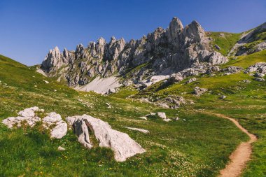 Karadağ 'ın Durmitor Ulusal Parkı' ndaki dağlarda yürüyüş parkuruna sahip manzaralı bir dağ manzarası. Güneşli yaz sabahında Bobotov Kuk 'a giden Zupci tepeleri ve yamaçtaki yürüyüş rotası..