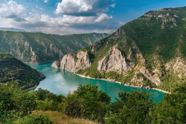 Durmitor yüksek dağlarının eteklerindeki Piva nehri kanyonundaki Turkuaz Piva Gölü. Piva Doğa Parkı, doğa severler için popüler bir yer. Balkanlar genelinde doğal simgeler ziyaret edilecek.