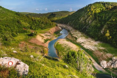 Dağlar arasında akan Uvac nehri ve yeşil ağaçlık tepeler ile dağ manzarası. Sırbistan 'daki Uvac Özel Doğa Rezervindeki Panorama. Balkanlar 'ın doğal güzelliklerini araştırıyor.