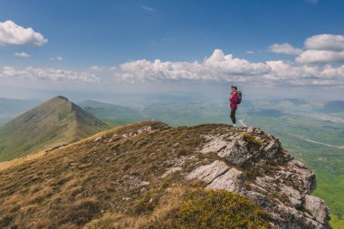 Suva Planina 'nın dağ yamacında duran sırt çantalı gezgin kadın manzaranın tadını çıkarıyor. Güzel manzaralarda tek başına gezen dişi turist. Macera, seyahat, aktif insanlar konsepti.