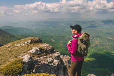 Sırt çantasıyla dağ manzarasında gezen bir gezgin kadın. Dişi turist tek başına seyahat ediyor, tek başına yürüyor, dağ manzarasında yükseklere seyahat etmekten hoşlanıyor. Macera yolculuğu, aktif yaşam tarzı konsepti.