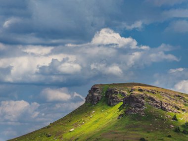 Tri Cuke 'un yaz manzarası kayalık çıkıntılar ve yemyeşil yamaçlarla dolu, bulutlu dramatik gökyüzüne karşı kurulmuş. Balkan Dağları 'nın engebeli doğal güzelliği, Stara Planina Dağları olarak da bilinir..