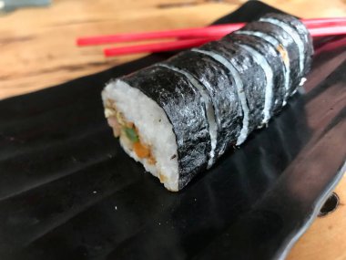 Siyah arka planda soya soslu suşi rulosu.