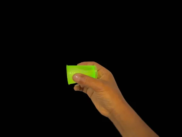 女性手握着一把绿色钥匙 与黑色背景隔离 并有复制空间 显示某物的钥匙 — 图库照片