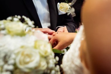 hands, wedding rings and marriage vows the groom holds and puts a wedding ring on the bride's finger
