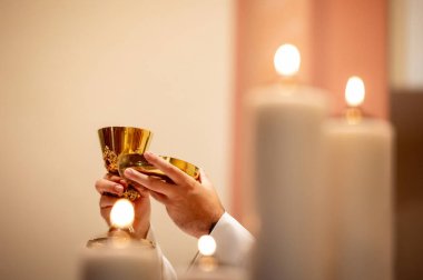 interiors and details in catholic church view of the altar, candles, priest and the chalice