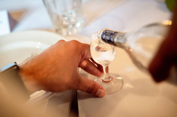 руки человека, наливающего алкоголь в стакан