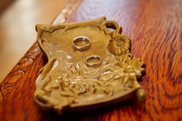 wedding rings and details wedding rings on a brass platter standing on a wooden table