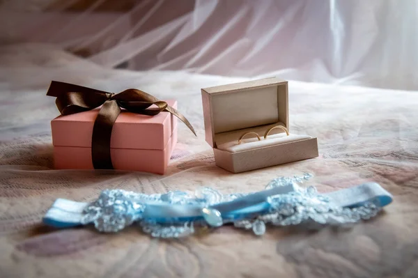 bride and groom's wardrobe and items of clothing blue bridal garter lying on the bed against the background of a blurred white veil