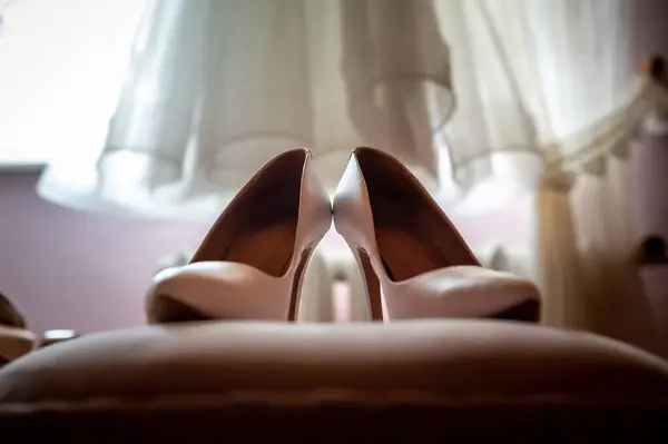 bride and groom's wardrobe and items of clothing bride's stiletto shoes on the background of a blurred wedding dress