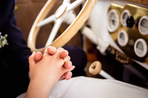 decorations and details on the car for the wedding intertwined hands of the bride and groom inside a white vintage car with a wooden steering wheel in the background