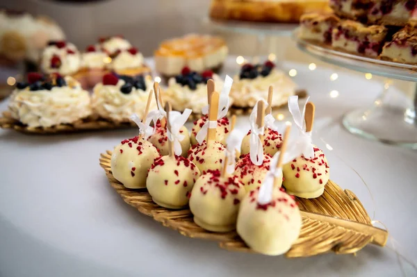 sweets, cake and cookies sweet balls on a stick in white chocolate with sprinkles