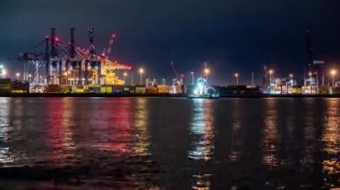 Akşamları çalışan bir Polonya konteynır limanında zaman kaybı. Dalgalanan su, ışıkların yansımaları ve gökyüzündeki bulutların akışı..