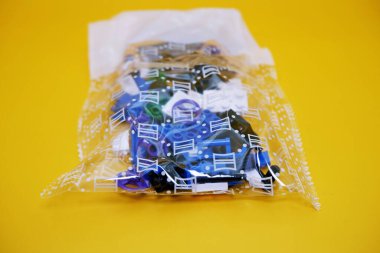 Hâlâ plastikte olan oyuncak parçaları koleksiyonu. Sarı arka planda izole edilmiş bir oyuncak yığını. Onları tuğla istifi gibi istifleyerek oynanan oyuncaklar..