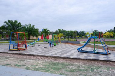 Parkta slaytlar, tahterevalliler ve sallanan sandalyelerden oluşan bir oyun parkı..