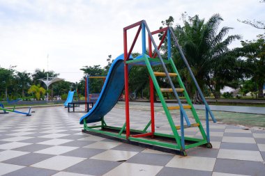 Çocukların parkta oynaması için demir merdivenli mavi kaydırak.