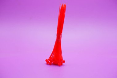 Mor arka planda izole edilmiş kırmızı kablo bağları. Kablo bağı ya da kablo bağı, çeşitli amaçlar için kullanılabilecek kayışlar.