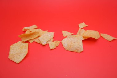 Geometrik şekilli patates cipsi ve ekmek kırıntıları kırmızıda izole edildi.