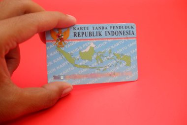 Endonezya kimlik kartı parlak kırmızı bir arka plana yerleştirilmiş. Kartın arkası açıkça görülüyor, tasarımını ve detaylarını gösteriyor..