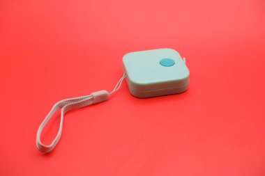 Kırmızı arka planda yeşil mezura izole edildi. Vücut ölçüleri için esnek terzi bandı, koyu renk kontrastıyla sunulmuştur.